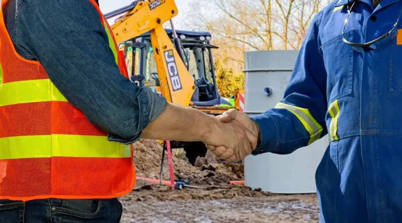 Uścisk dłoni między instalatorem a klientem po zakończeniu montażu przydomowej biologicznej oczyszczalni ścieków.